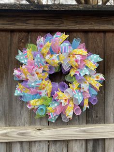 a colorful wreath hanging on the side of a wooden fence