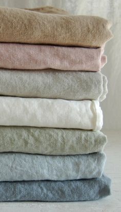 a stack of folded towels sitting on top of a white tablecloth covered in grey and pink colors