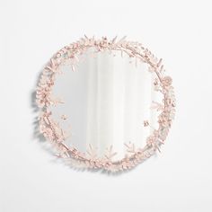 a round mirror with pink flowers on the side and a white wall in the background