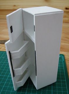 an open white refrigerator sitting on top of a cutting board next to a green mat