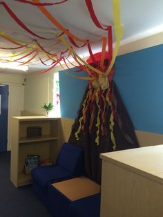 an office decorated with streamers and ribbons on the ceiling, along with a blue chair