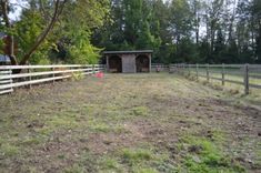 a fenced in area with an outhouse and horse pen on the other side