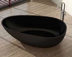 a black bath tub sitting on top of a wooden floor