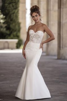 a woman in a wedding dress posing for the camera with her hands on her hips