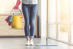 a woman holding a yellow bucket and mop