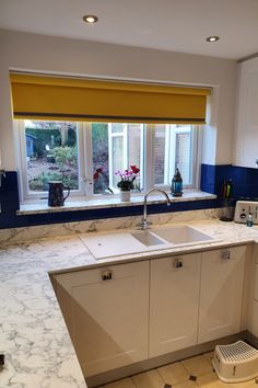 a kitchen with white cabinets and yellow blinds on the window sill above the sink