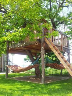 a tree house with a hammock in the yard