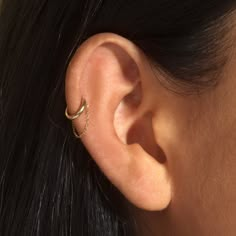 a close up of a person wearing a gold ear cuff with an arrow on it