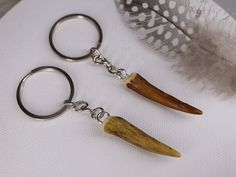 two pieces of wood are attached to the keychain with silver hooks and an animal's tooth