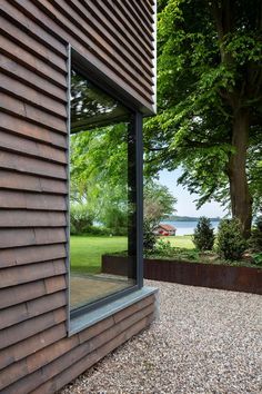 an open window on the side of a wooden building next to a field and trees