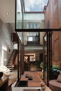 the interior of an apartment building with glass walls and wooden stairs leading up to the second floor