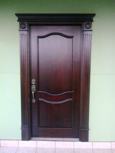 a brown wooden door sitting on the side of a green wall next to a white tiled floor