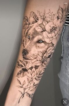 a person with a tattoo on their arm that has flowers and a wolf's head