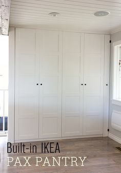 an empty room with white cupboards and windows on the wall, in front of a wooden floor