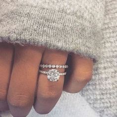 a woman's hand with a diamond ring on it and a sweater over her