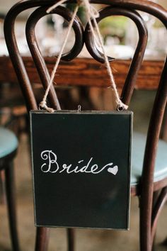 a sign hanging from the back of a chair that says,'bride'on it