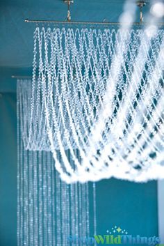 a chandelier hanging from the ceiling in a room with blue walls and white curtains