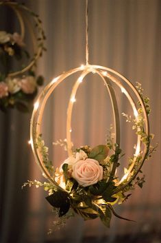 two circular lights hanging from the ceiling with flowers and greenery on them, one light is lit up