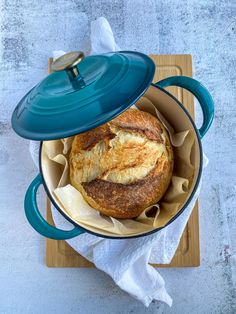 a blue pot with some bread in it on top of a cutting board and napkins