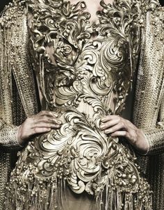 a woman in a gold dress with an elaborate design on it