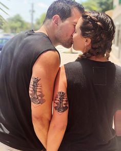 a man and woman kissing each other with tattoos on their arms