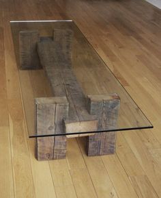 a wooden bench sitting on top of a hard wood floor next to a glass table