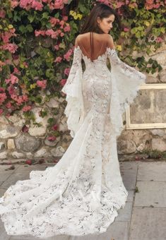 the back of a woman's white wedding dress with long sleeves and open shoulders