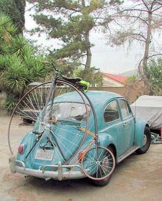 an old blue car with a bicycle on the back