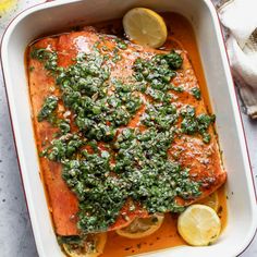 baked salmon with herbs and lemons in a casserole dish