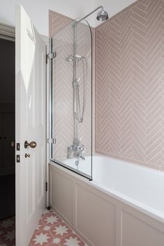 a bathroom with pink and white tiles on the floor, shower stall and bathtub