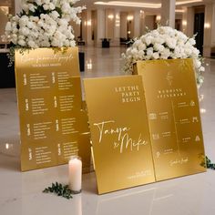 two gold menus sitting on top of a table next to a white flower arrangement