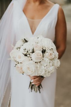 a bride holding a bouquet of white flowers