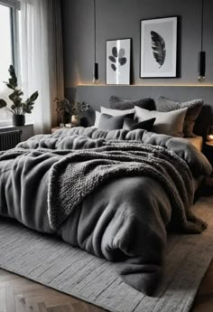 a bedroom with dark gray walls and grey bedding, two framed pictures on the wall