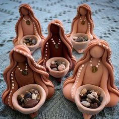 seven ceramic nativity figurines sitting on a table with rocks in their bowls