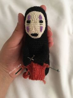 a hand holding a small crocheted doll