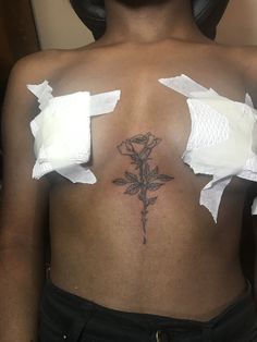 a woman with torn up pieces of paper around her back and shoulder, holding a rose tattoo on her left side