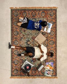 a man laying on top of a rug next to an open book and other items