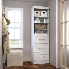 a white cabinet with drawers and towels in the corner next to a window, on a wooden floor