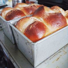 two loafs of bread sitting on top of a metal pan covered in powdered sugar