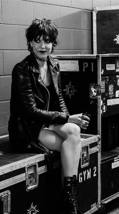 black and white photograph of a woman sitting on top of some trunks with her legs crossed