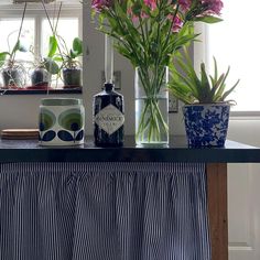 flowers in vases and bottles on a table with a blue and white striped cloth