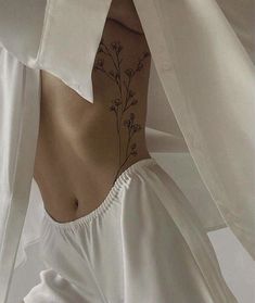 the back of a woman's white shirt with flowers on her chest and bottom