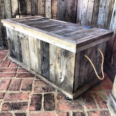 a wooden box sitting on top of a brick floor next to a wall covered in wood planks