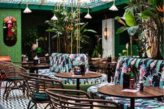 an outdoor restaurant with tables and chairs covered in colorful cushions, potted plants and hanging lights