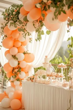 an orange and white dessert table with balloons