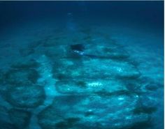 a man swimming in the ocean next to some rocks