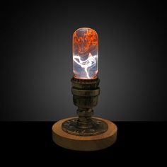 a small lamp with an orange and white light in it's glass dome on top of a wooden stand