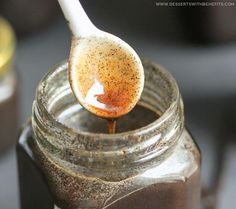 a spoon full of brown liquid being poured into a jar with some sort of substance in it