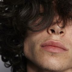 a close up of a person with curly hair and no shirt looking at the camera