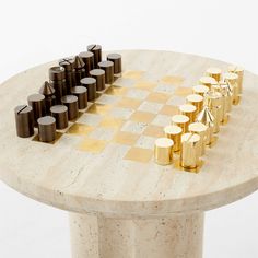 a marble chess board with gold and black pieces on it's side, sitting on top of a marble table